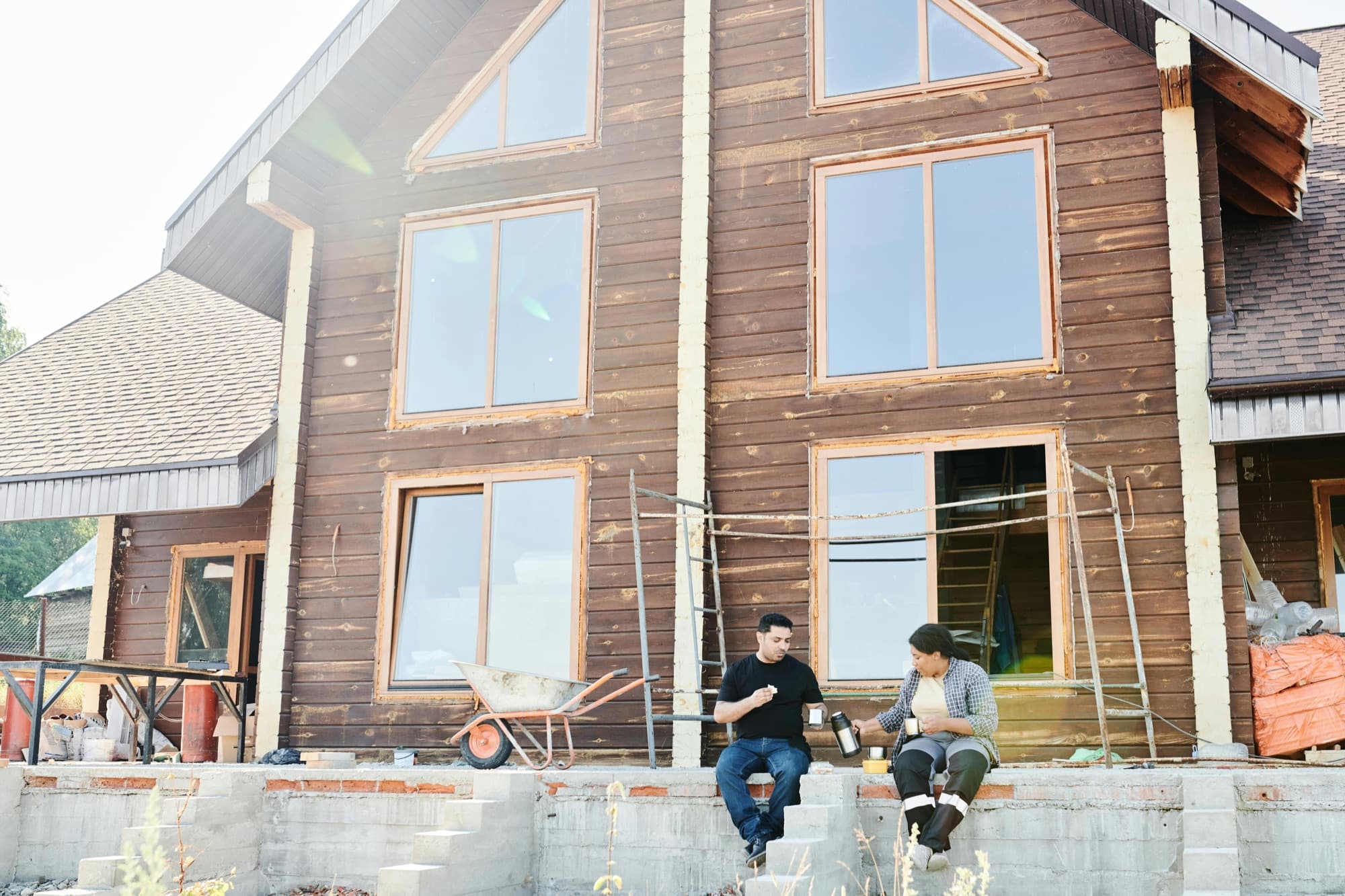 Two crew members working together on a residential install at a wood-sided home