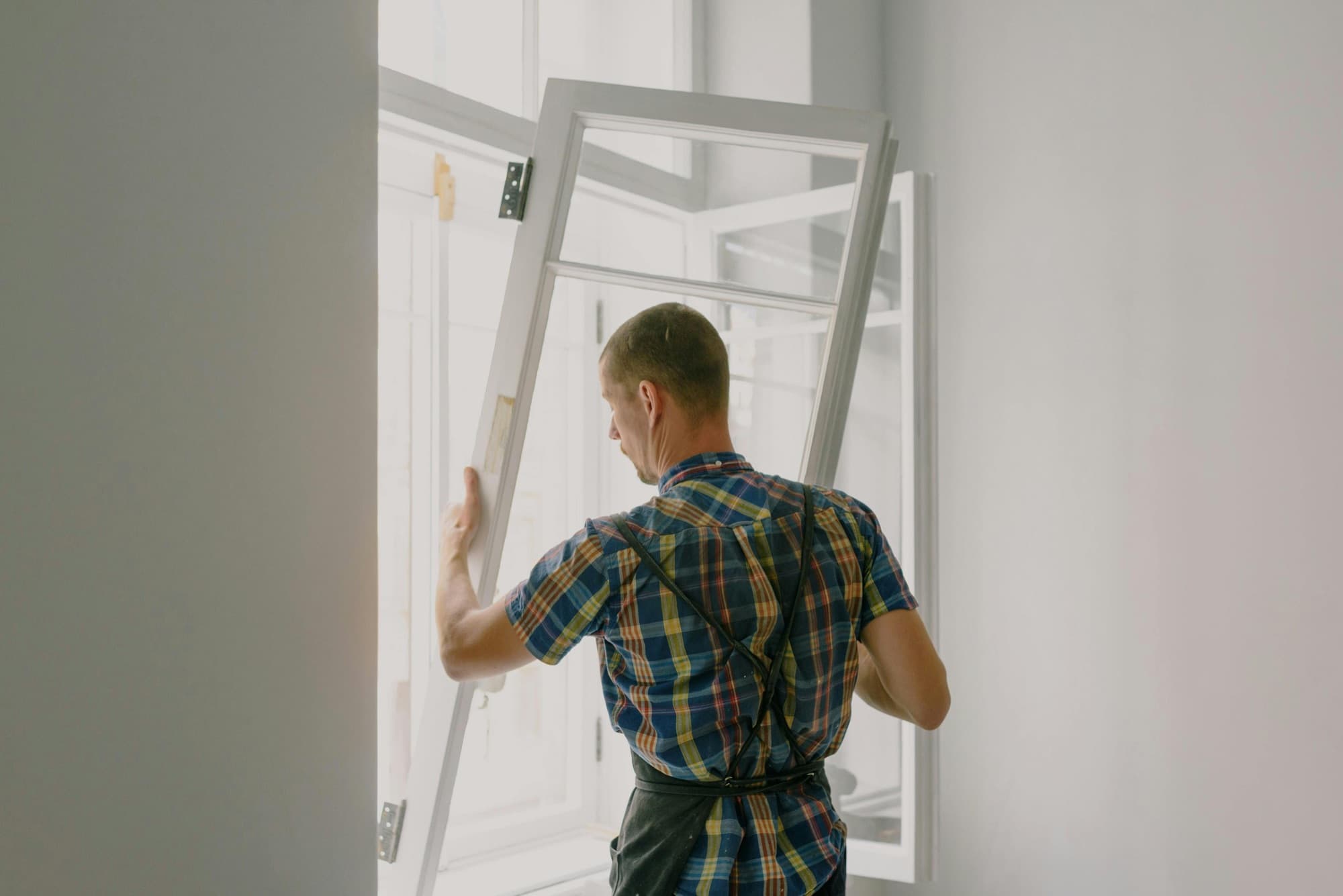 Window installer fitting a residential window during a multi-family install